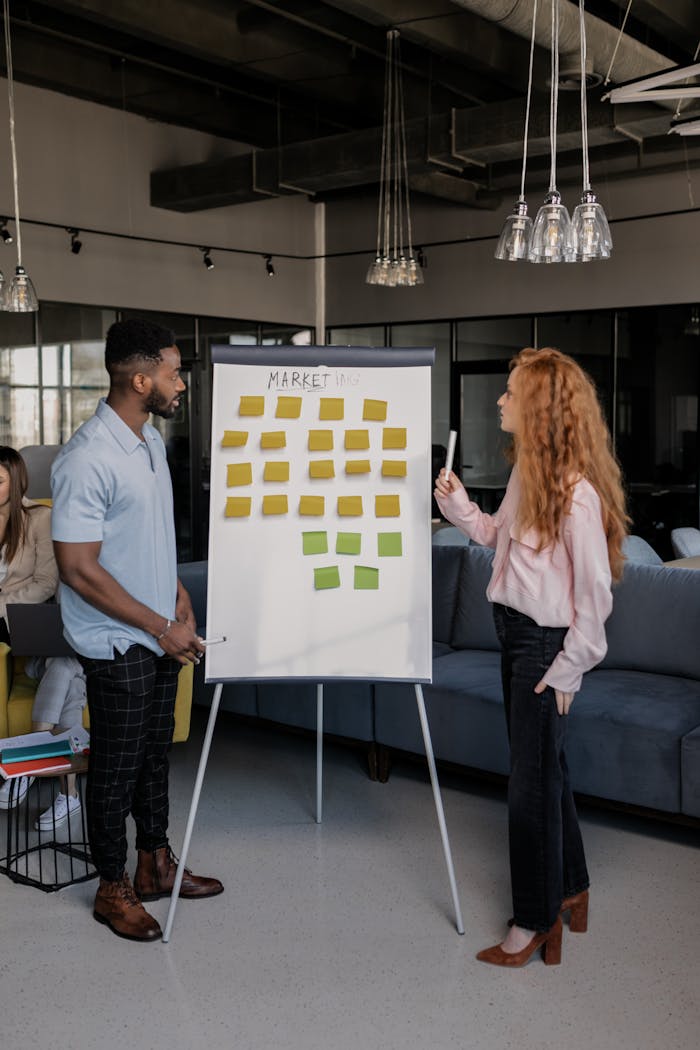 Colleagues collaborating on marketing strategy with sticky notes on a whiteboard in a modern office setting.