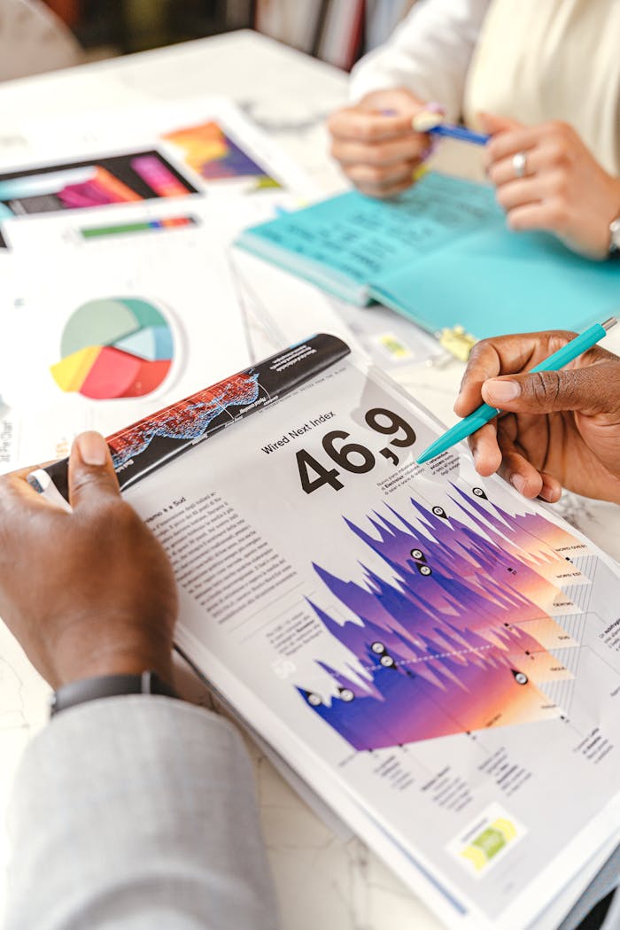 Hands discussing vibrant data charts during a business meeting, with papers and diagrams.